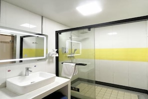 A bathroom with a white sink, a mirror, and a glass-enclosed shower. - Jingying Hotel (Kunshan)