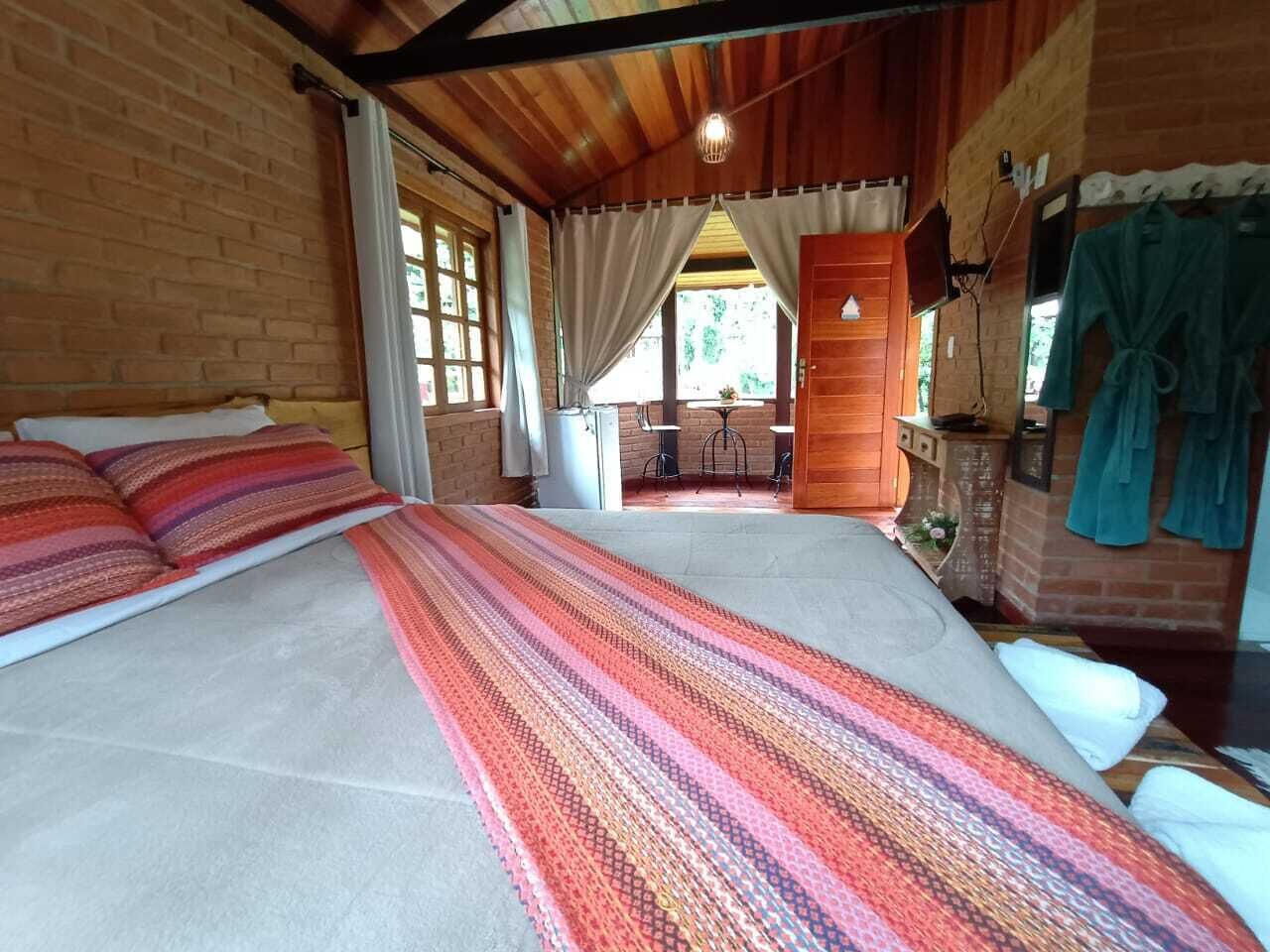 A spacious room with a large bed, a wooden ceiling, and a view of the outdoors through a window.