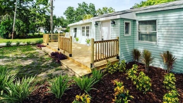 A single-story mobile home with a front porch and a small deck. - The Bungalow on Betty (Clearwater)