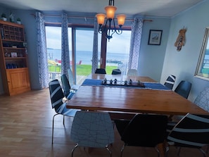 A dining area with a wooden table, chairs, and a view of the sea.