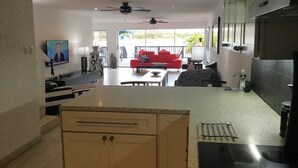 Una cocina moderna con encimera, armarios y un comedor con sofá rojo y una cafetera.