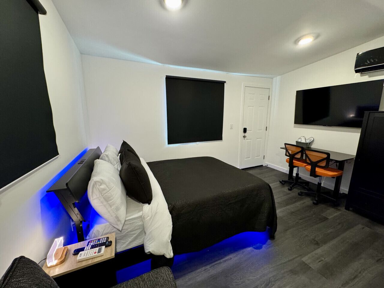 Une chambre d’hôtel moderne équipée d’un lit, d’un bureau avec un ordinateur, d’une télévision et d’une porte.