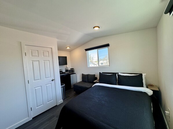 A bedroom with a bed, a desk, and a window.