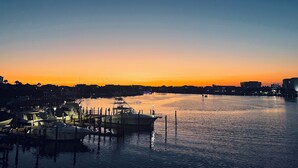 Un port de plaisance au crépuscule, avec des bateaux amarrés et une surface d’eau calme qui reflète le ciel.