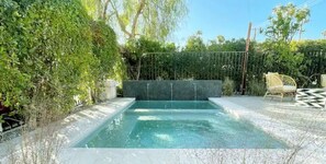 Relax by the pool surrounded by lush vegetation and a seating area.