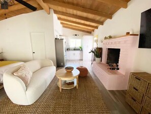 Cozy living space with a high ceiling, sofa, side table, and fireplace.