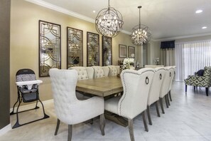 A dining room with a large wooden table, upholstered chairs, and decorative wall mirrors.