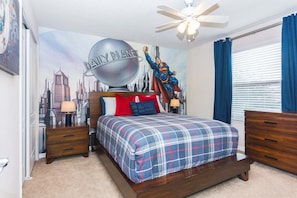 Ein Schlafzimmer mit Stadtbild-Wandgemälde, einem Bett mit Karo-Bettwäsche, einem Deckenventilator und einem Fenster mit Vorhängen.