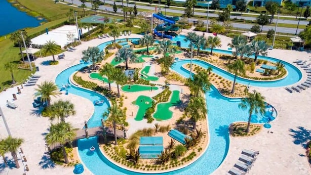 An aerial view of a resort with a large swimming pool, multiple water slides, and a golf course. - Roomy Family Home-Sleeps 16 | 109 (Kissimmee)