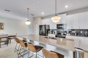A modern kitchen with a central island, stainless steel appliances, and pendant lighting.