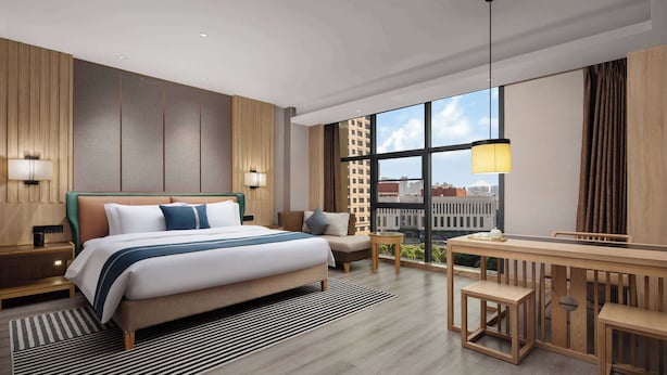 A modern hotel room with a large bed, a desk, and a view of the city. - Microtel by Wyndham Changsha Yuhua (Changsha)