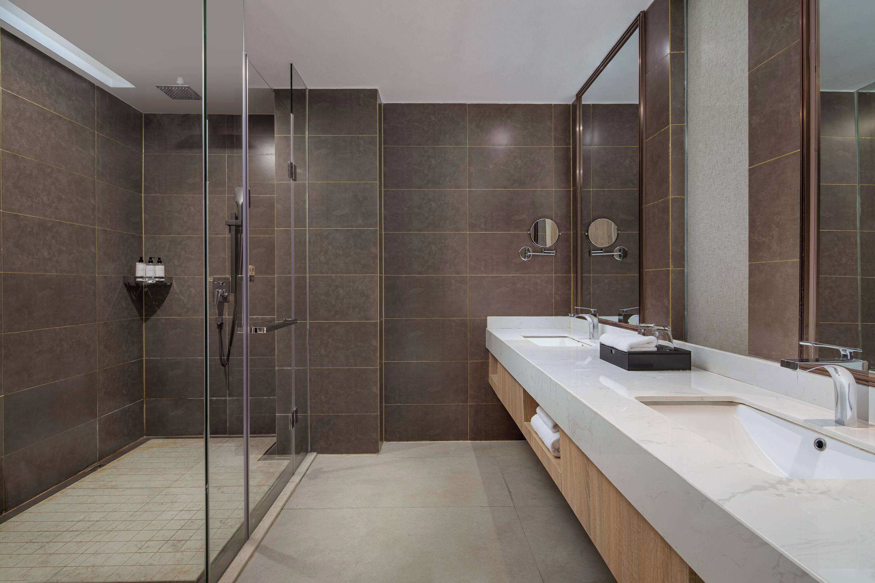 A modern bathroom with a glass-enclosed shower, a large mirror, and a dual sink vanity.