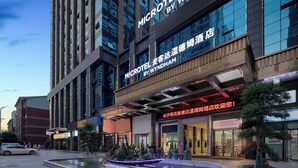 A modern hotel with a prominent sign, a landscaped area with a water feature, and a well-lit entrance. - Microtel by Wyndham Changsha Yuhua (Changsha)