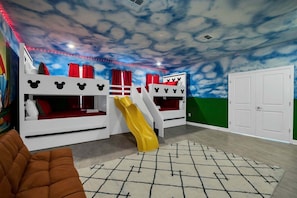 Una sala de juegos infantil con literas, un tobogán y una puerta.