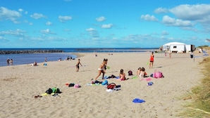 Une plage avec des gens, une tente et divers objets éparpillés sur le sable.
