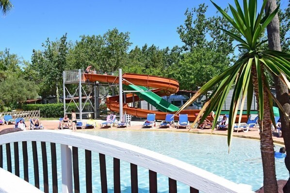 Un área de piscina con tobogán y sillas de descanso.