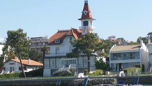 Une ville côtière dotée d’un imposant clocher d’église, d’eaux calmes et d’un petit bateau amarré près du rivage.