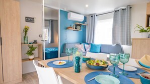 Une cuisine moderne avec un coin repas, comprenant une table en bois mise avec des assiettes, des verres et un saladier rempli de salade.