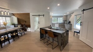 Una cocina moderna con una isla central, suelo de madera y vistas al exterior.