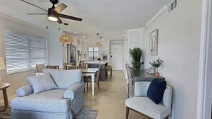 Una sala de estar moderna con un sofá, una silla, una mesa de comedor y una cocina al fondo.