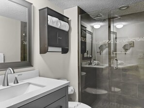 Une salle de bain moderne avec une douche à parois de verre, un grand miroir et un lavabo blanc.
