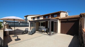 A patio with outdoor furniture, a glass enclosure, and a sliding door.
