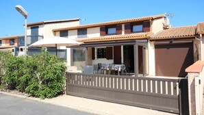 A two-story building with a balcony, a covered outdoor seating area, and a gated entrance.