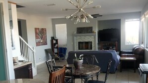 A modern living room with a dining area, a fireplace, and a television.