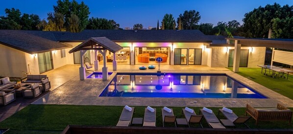A modern house with a swimming pool, outdoor seating, and a covered patio area.