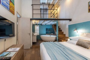 Ein modernes Schlafzimmer mit einem großen Bett, einer integrierten Badewanne und einer Treppe zu einer oberen Ebene.