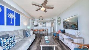 A modern living room with a gray sofa, wooden coffee table, and a ceiling fan. - Oceanfront Luxury Condo - 3BD with Gorgeous Views - Oceanfront Pool (North Myrtle Beach)