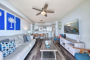 A modern living room with a gray sofa, wooden coffee table, and a ceiling fan.