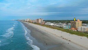 A coastal cityscape with a wide beach, buildings along the shore, and a clear sky. - Oceanfront Luxury Condo - 3BD with Gorgeous Views - Oceanfront Pool (North Myrtle Beach)