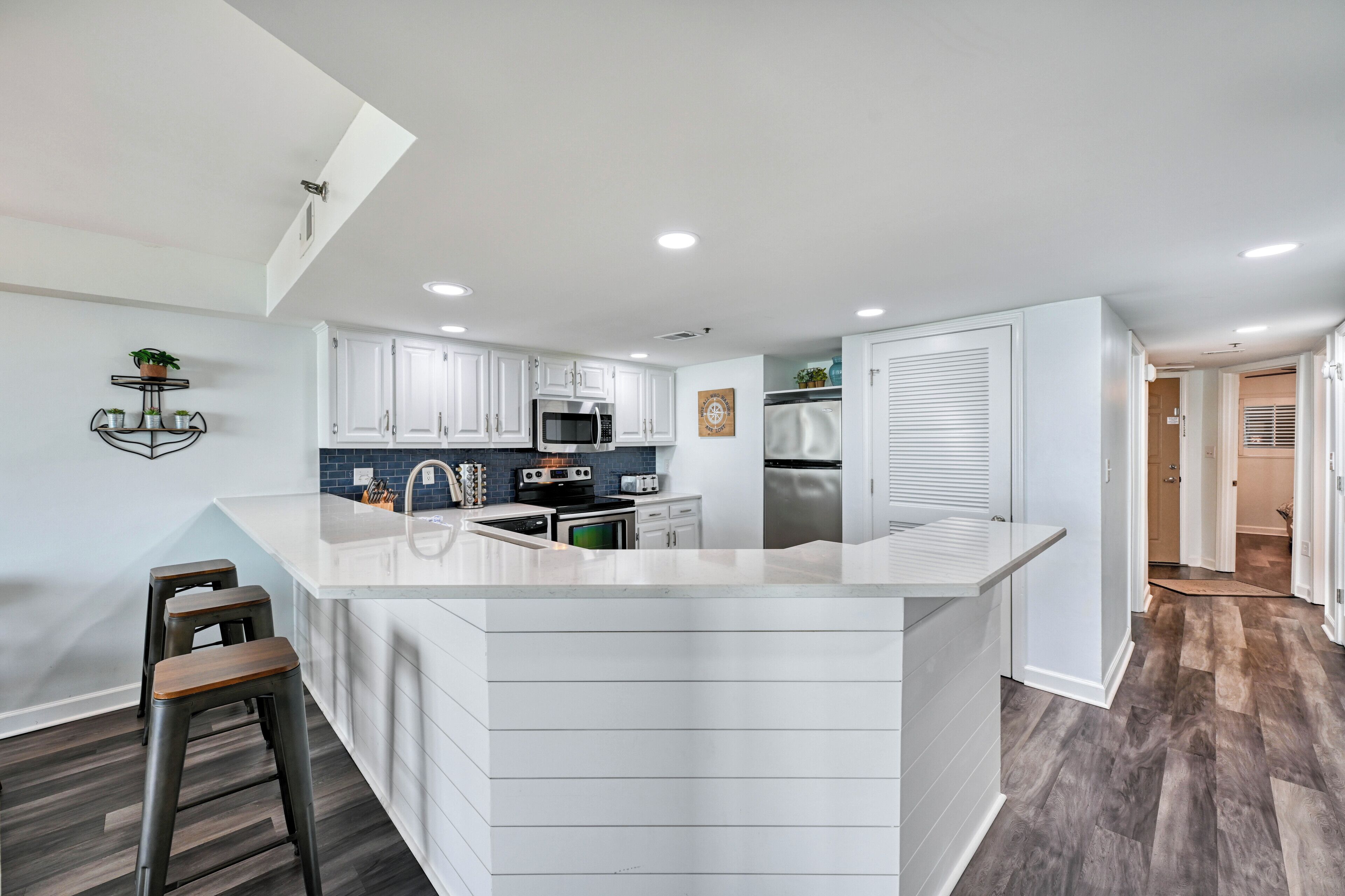 Una cocina moderna con armarios blancos, una isla central y un microondas integrado.