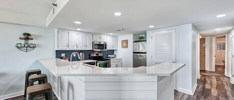 Una cocina moderna con armarios blancos, una isla central y un microondas integrado.