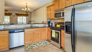 A modern kitchen with wooden cabinets, stainless steel appliances, a dishwasher, and a patterned rug. - Decatur Vacation Rental ~ 5 Mi to Downtown Decatur (Decatur)