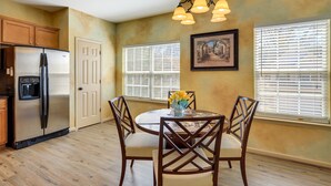 A kitchen with wooden cabinets, a stainless steel refrigerator, a dining table with chairs, and a chandelier. - Decatur Vacation Rental ~ 5 Mi to Downtown Decatur (Decatur)