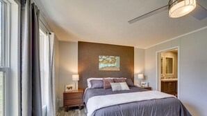 A bedroom with a large bed, bedside tables, a headboard, a painting, and a bathroom visible through an open door. - West Mineral Vacation Rental Home w/ Fire Pit! (West Mineral)