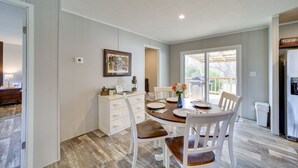 A dining area with a wooden table and white chairs, a white cabinet, and a painting on the wall. - West Mineral Vacation Rental Home w/ Fire Pit! (West Mineral)