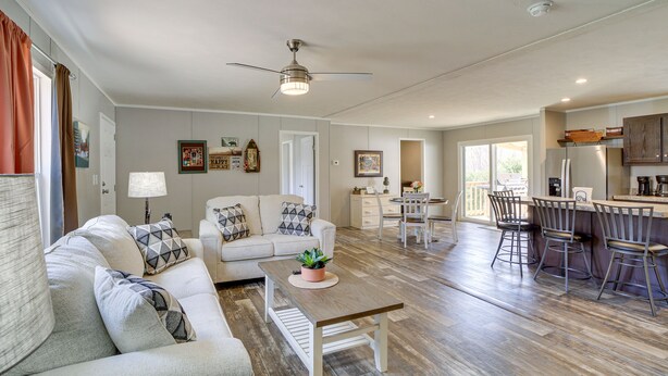 A spacious living room with a sofa, coffee table, and a dining area with chairs and a kitchen in the background. - West Mineral Vacation Rental Home w/ Fire Pit! (West Mineral)