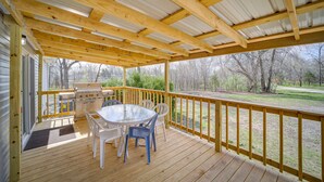 A covered outdoor deck with a table and chairs, a grill, and a view of a park. - West Mineral Vacation Rental Home w/ Fire Pit! (West Mineral)