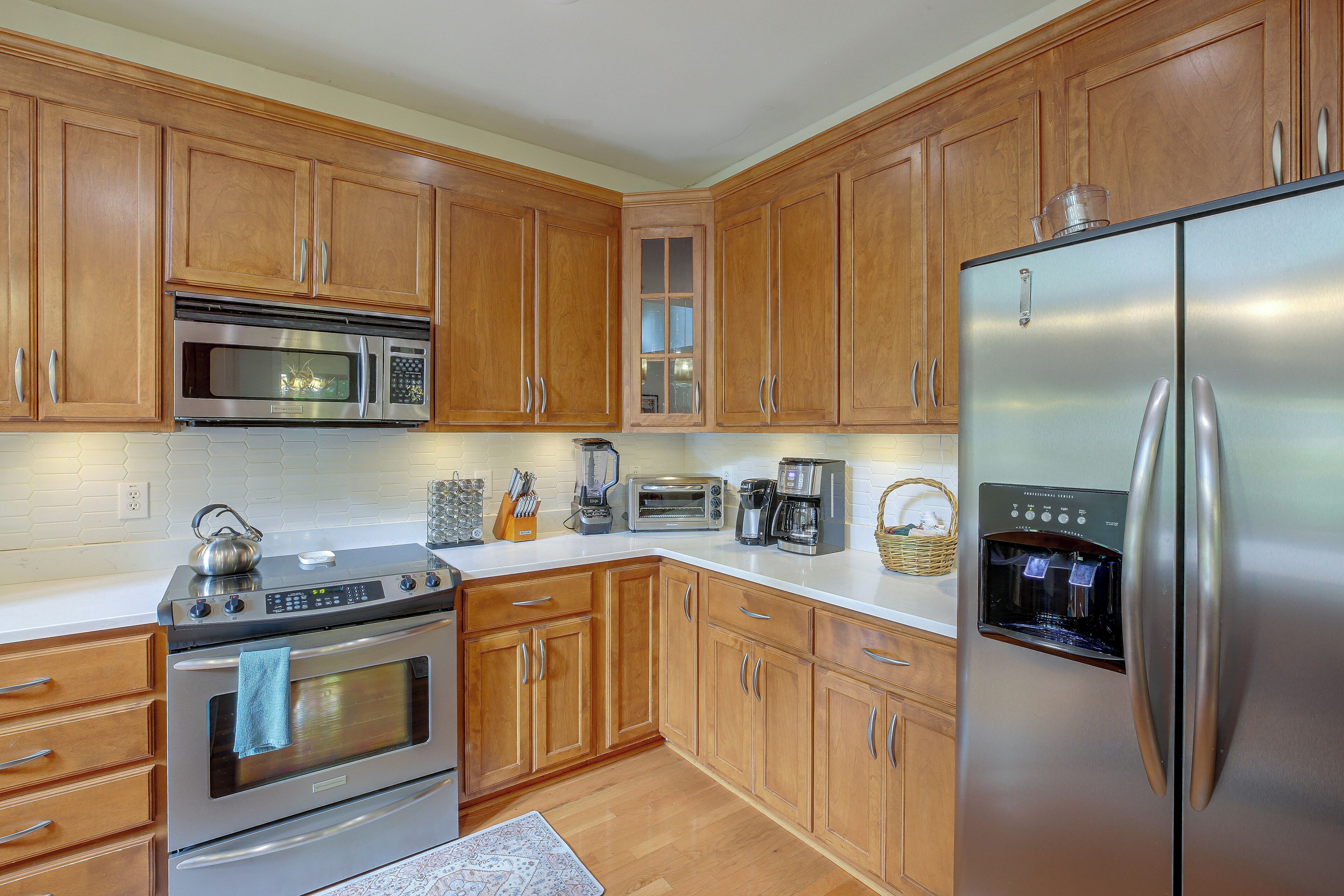 A kitchen with wooden cabinets, stainless steel appliances including a refrigerator, oven, and microwave, and a coffee maker.