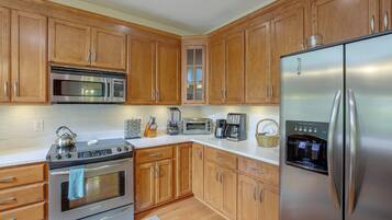 A kitchen with wooden cabinets, stainless steel appliances including a refrigerator, oven, and microwave, and a coffee maker.