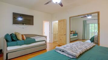 A bedroom with a bed, a sofa, a television, and a ceiling fan.