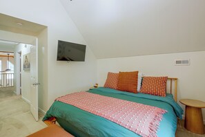A bedroom with a bed, a television mounted on the wall, and a small wooden table.