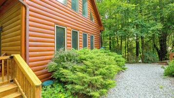 A log cabin with a wooden staircase and a gravel pathway leading to the entrance.