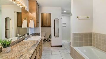 A modern bathroom with a granite countertop, a bathtub, and a walk-in shower.