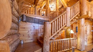 A wooden staircase with a handrail leading to a second-floor area, a bench, and a lamp on the floor.