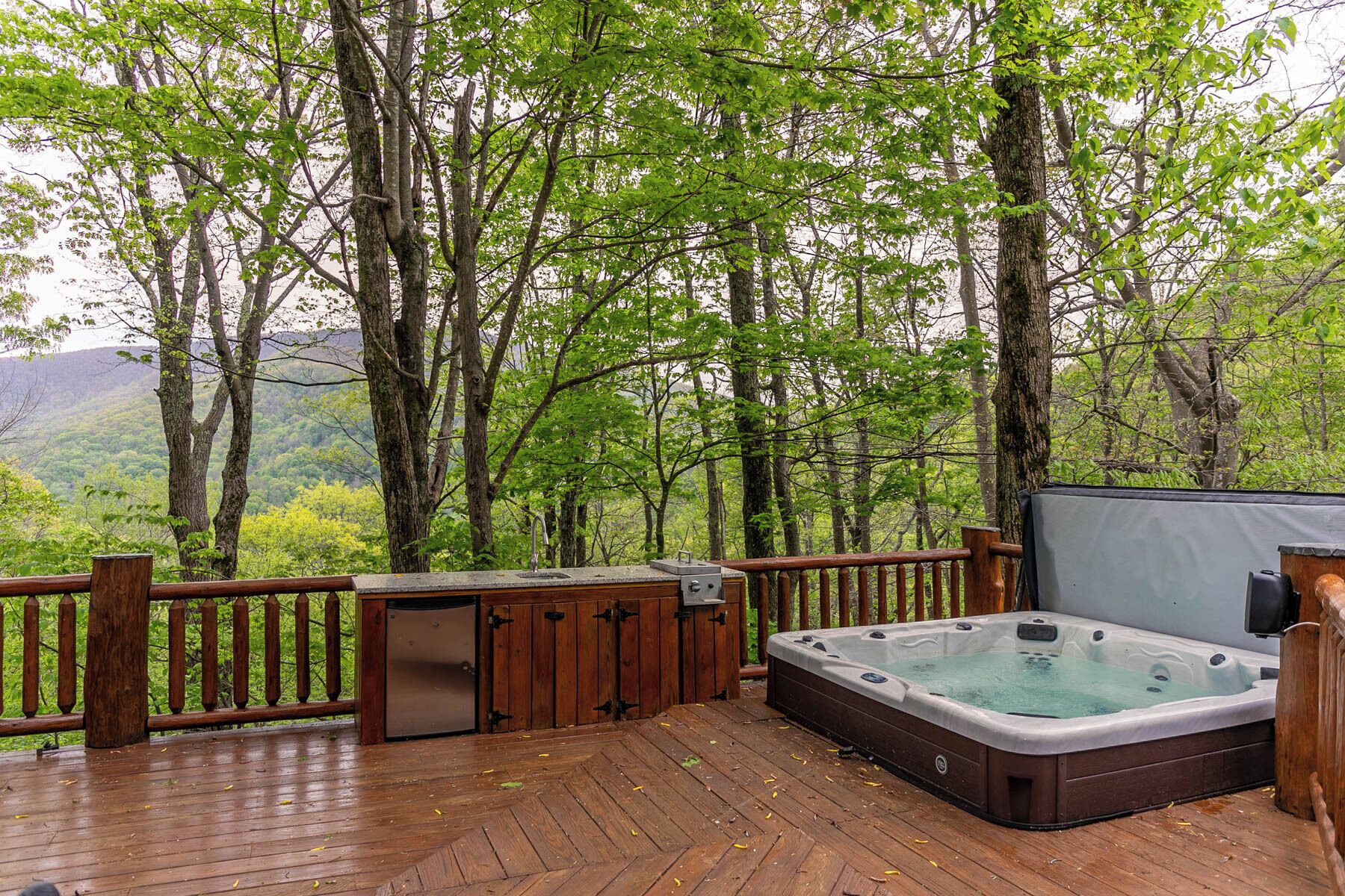 A wooden deck with a hot tub, a small refrigerator, and a television.