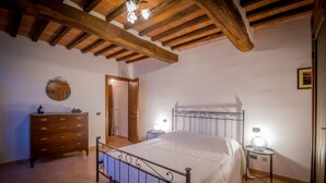 Ein Schlafzimmer mit Holzbalkendecke, einem Metallbettgestell, einem Schminktisch und Nachttischlampen.
